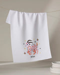 A white tea towel from Heather Zhou, called "Daring Aries," hangs on a line with a cute pink ram illustration, stars, and "Aries" beneath. A stack of white dishes sits in the lower right corner.