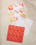 The Geometry Fun Franks set features three square absorbent dishcloths with playful hot dog and heart patterns in red, yellow, and pink, arranged on a beige marble surface.