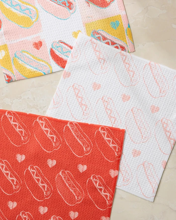 Three absorbent Geometry Fun Franks dishcloths with hot dog and heart designs, in red, white, and multicolor, are displayed on a light marble surface—perfect for adding a playful touch to your kitchen.