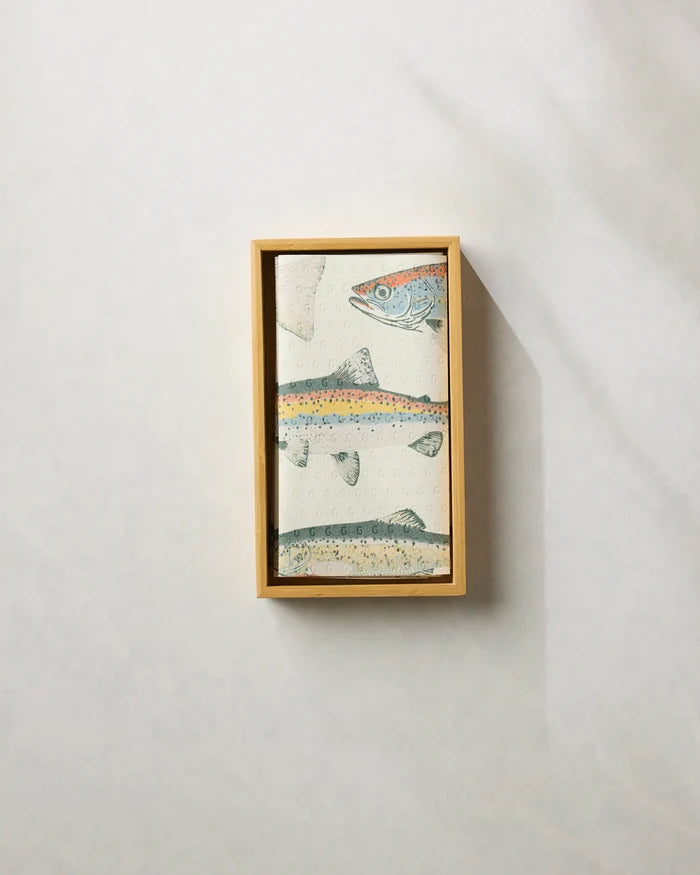 A neatly folded Geometry "Hooked on Fishing" reusable paper towel featuring an illustrated fish design sits in a rectangular wooden box against a light, textured background.