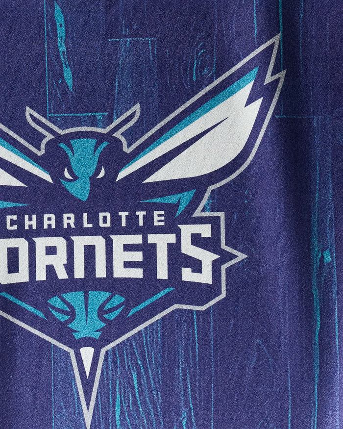The image shows the Hornets Zone towel by NBALAB x Geometry, featuring the Charlotte Hornets logo on a blue wood-textured background. This quick-drying workout towel is perfect for NBA fans and fitness routines.