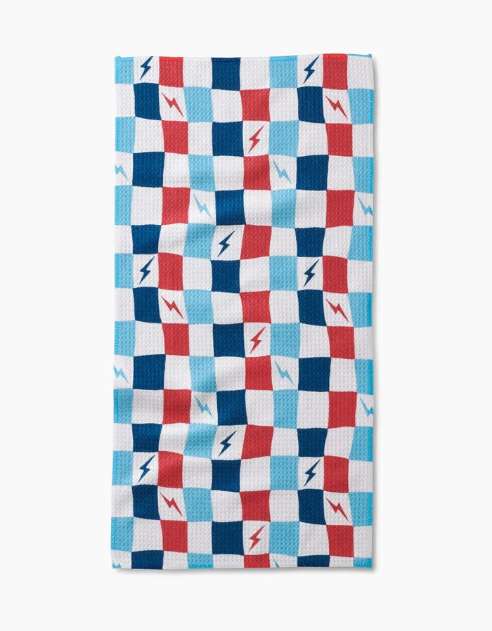 The Lightening Bolt Chess Bar Towel by Hufton Studio features a blue, red, and white checkered design with lightning bolts on Geoweave fabric, shown against a white background.
