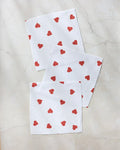 Geometry’s Love Toss dishcloth set features three white napkins adorned with small red hearts, arranged on a marble-like surface—an eco-friendly choice made from recycled materials.