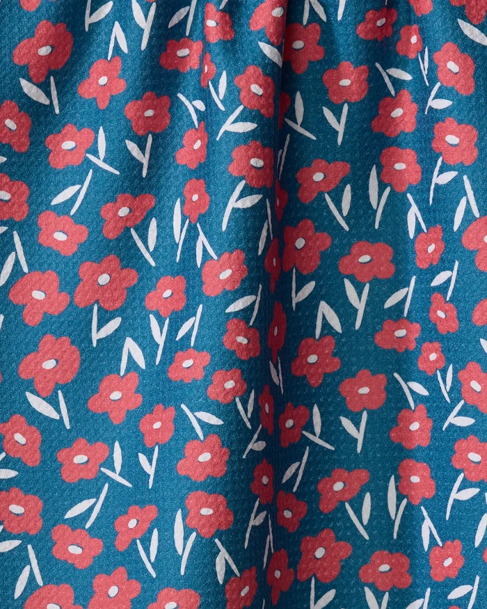 Luca Daisy Red by Hufton Studio features a blue fabric adorned with small red flowers and white leaves. This recycled tea towel has a soft texture and gentle folds, ideal for bringing charm to your kitchen.