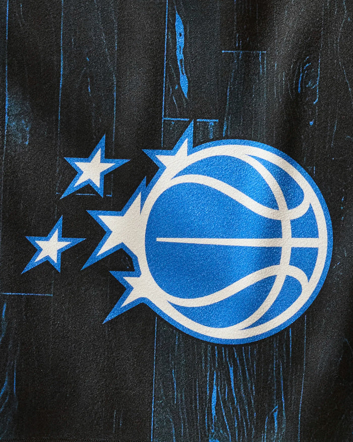 A blue and white basketball logo with three stars trailing on a black wood-textured background inspires the "Magic Zone" quick-dry fitness towel by NBALAB x Geometry.