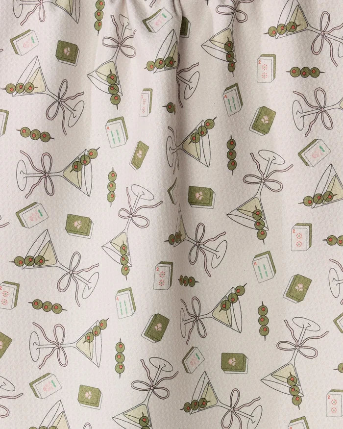 Martini Tiles by Geometry features a playful, patterned fabric showcasing martini glasses with olives, triangular sandwiches, and playing cards on a light background. The brown-outlined illustrations are accented in green and pink—ideal for use as a whimsical tea towel or kitchen towel made from recycled materials.
