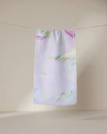 The GEOMETRY Province of Connacht bar towel features a pastel abstract watercolor design in purple, pink, green, and blue. Made from ultra-absorbent fabric, it hangs stylishly against a neutral background for both function and flair.