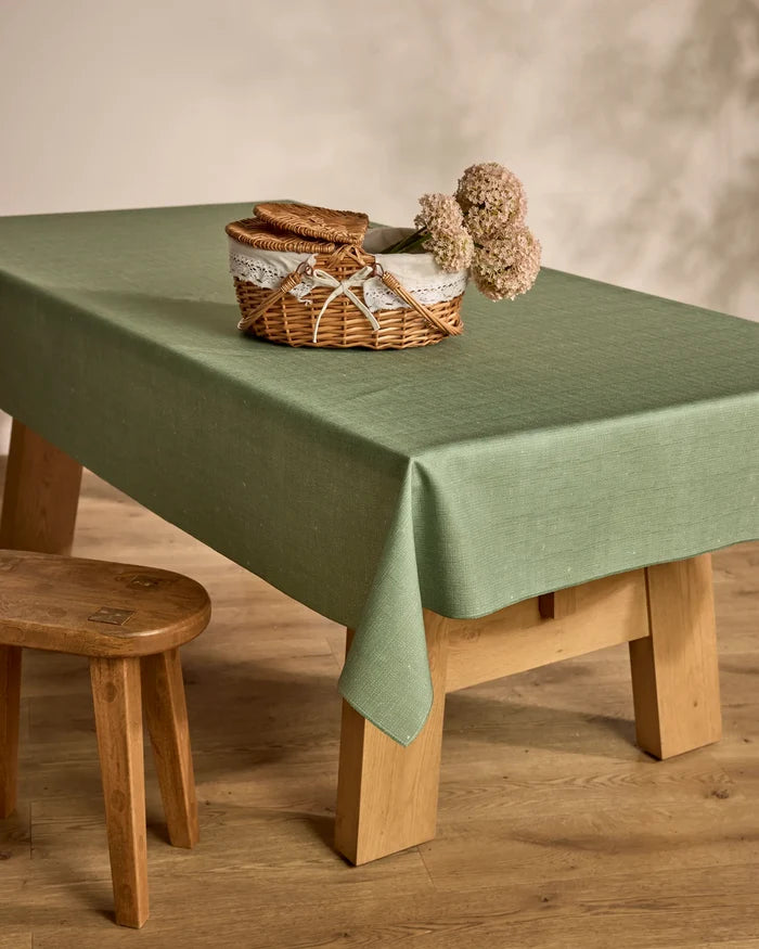 The Geometry Solid table is topped with a lightweight cloth, a wicker basket of brown napkins and pale hydrangeas, and sits on a wooden floor beside a small wooden stool.
