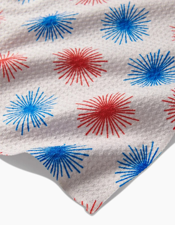 The Kayla Ann Sparkler Splash bar towel features white Geoweave fabric with a repeating red and blue starburst fireworks pattern printed across its textured surface.