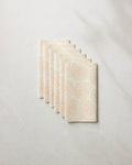 Seven eco-friendly Geometry Spira paper towels, featuring a light beige spiral shell pattern, are fanned out neatly on a light marble surface.