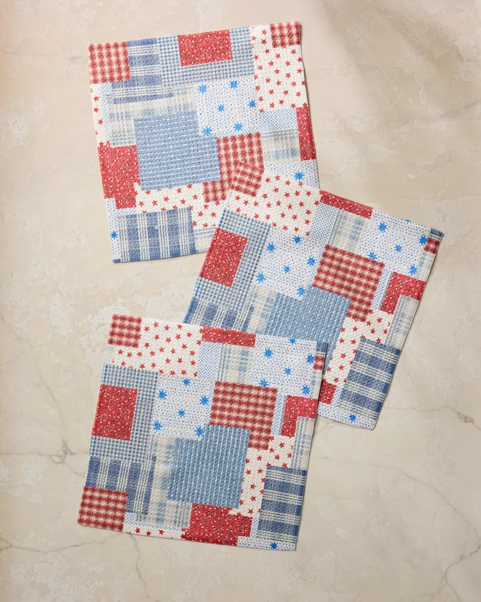 The Geometry Stars and Stitches set includes three square fabric napkins with a red, white, and blue patchwork of stars, checks, and stripes—perfect for adding festive flair to your kitchen.