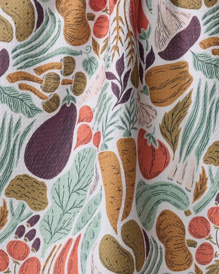 The Twila tea towel by Amy MacCready features hand-drawn carrots, tomatoes, and eggplants on a white background. Made from recycled materials, this ultra-absorbent towel has a slightly wrinkled, charming finish.
